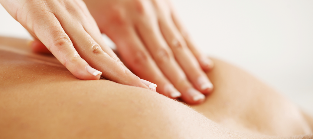 Hands press between the shoulder blades during a deep tissue massage.