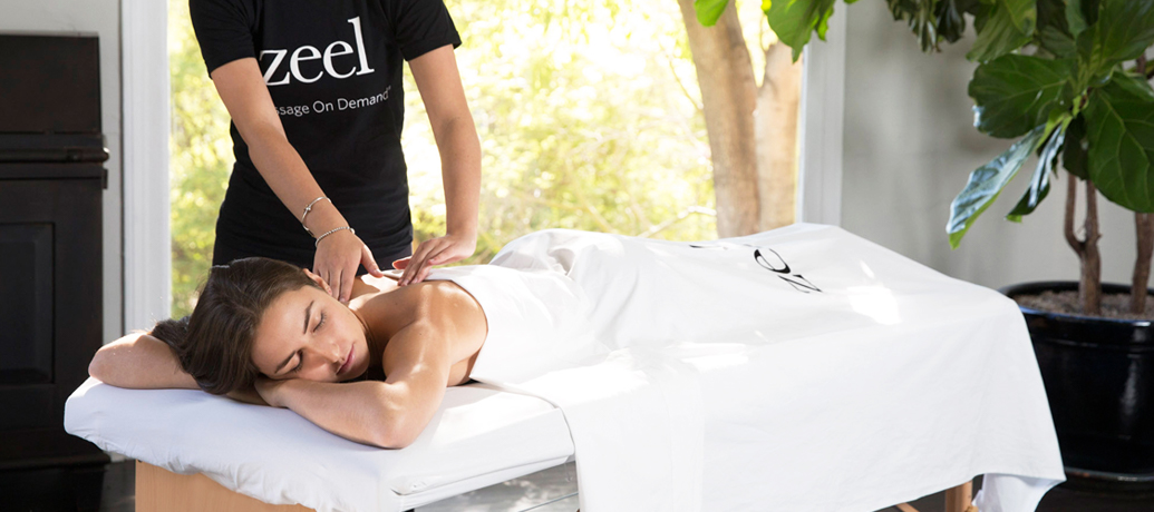 Woman relaxes on a massage table as she receives a luxury in-home massage experience from a Zeel Massage Therapist.