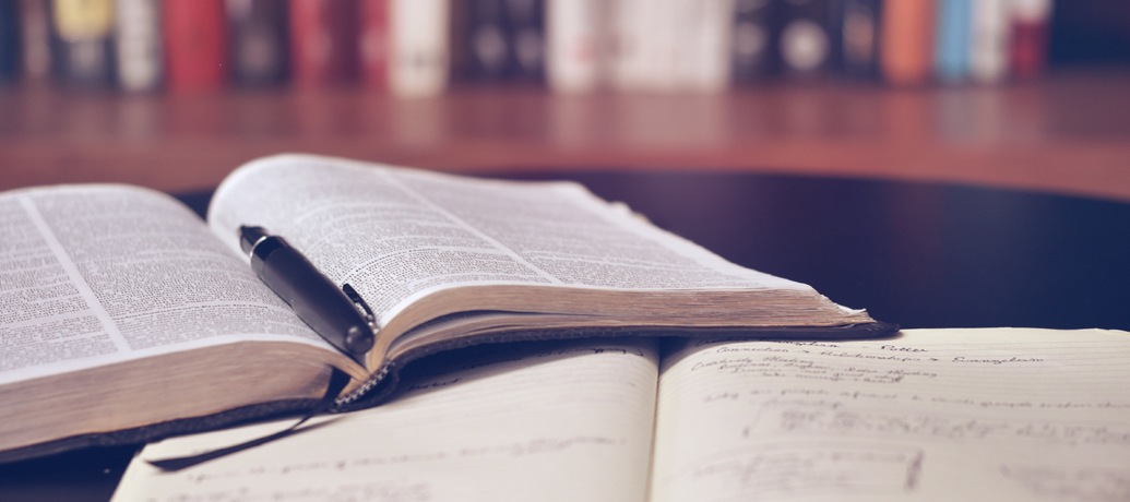 Books and study materials litter the desk of a busy massage therapy student.