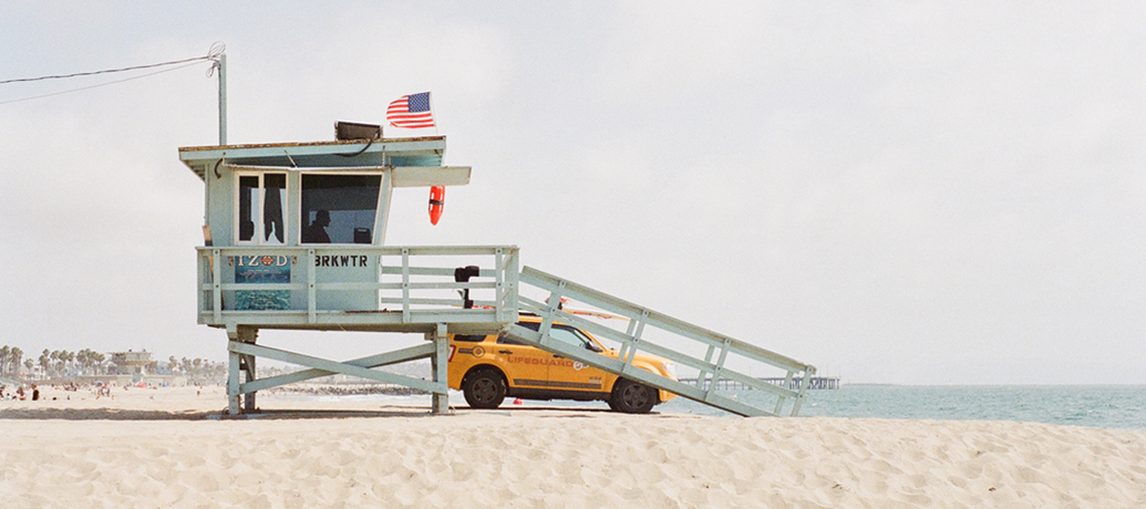 Lookout point has an American flag flying on a calm day at the beach.