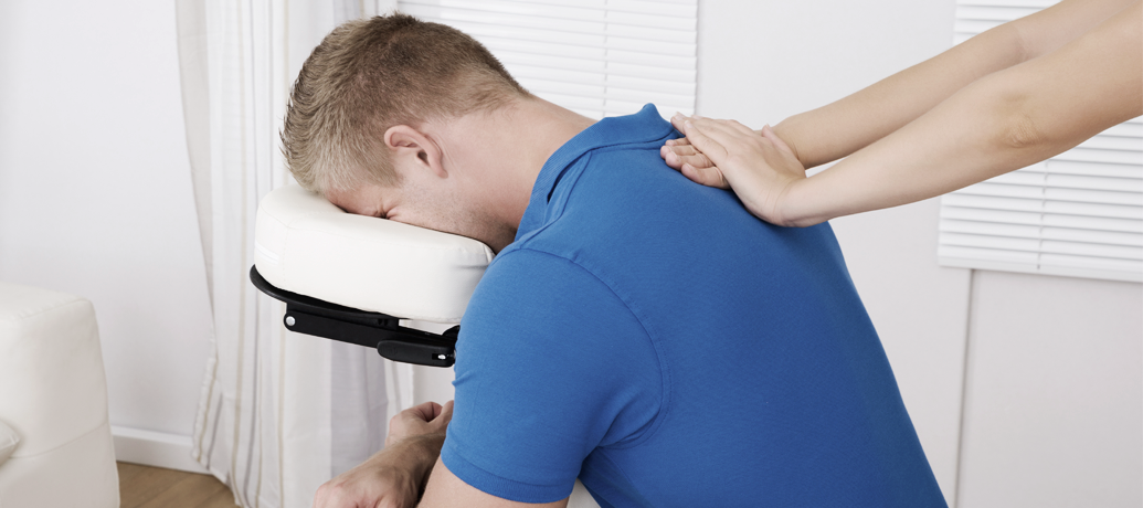 Man receives relaxing chair massage at the office in the middle of his work day