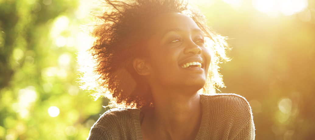 Woman smiles into the distance at sunset.