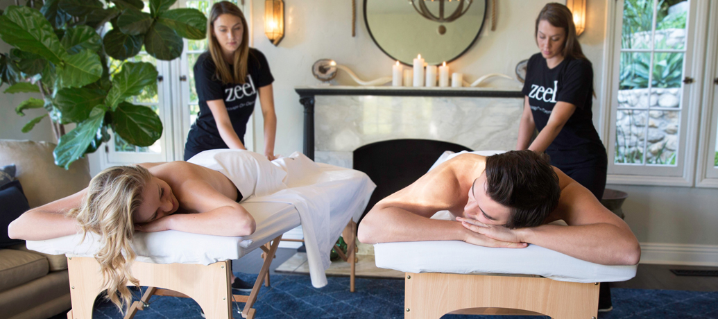 A man and woman enjoy a Zeel Couples Massage in the mini spa paradise created in their very own living room.