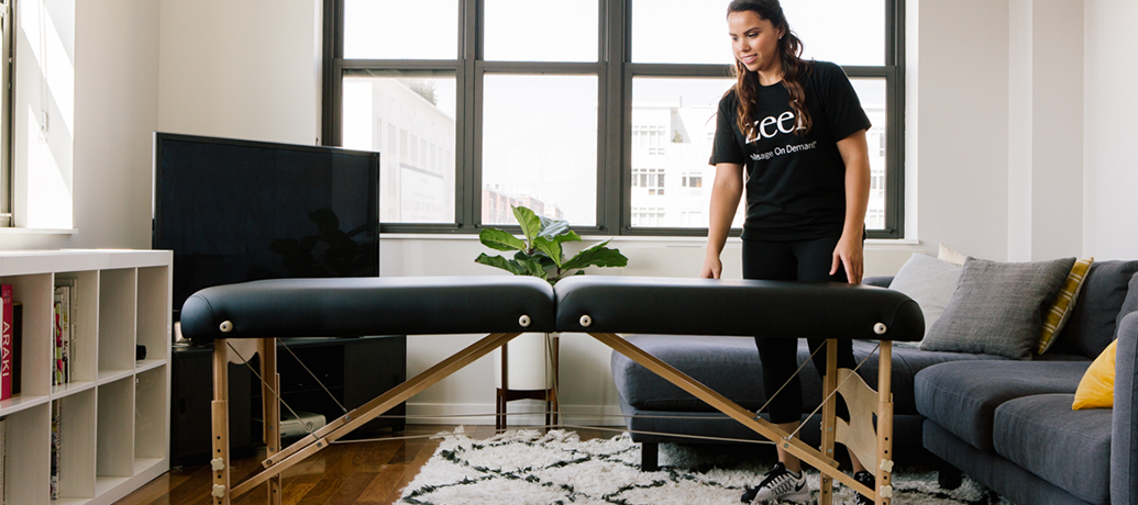 Zeel Massage Therapist setting up an in-home spa in a NYC living room.