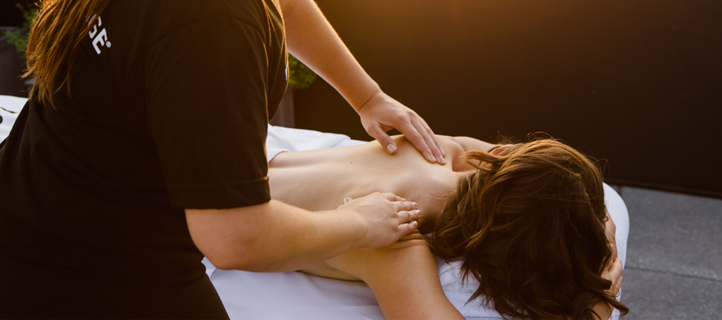 A woman relaxes on a massage table as a licensed massage therapist works on the client's back.