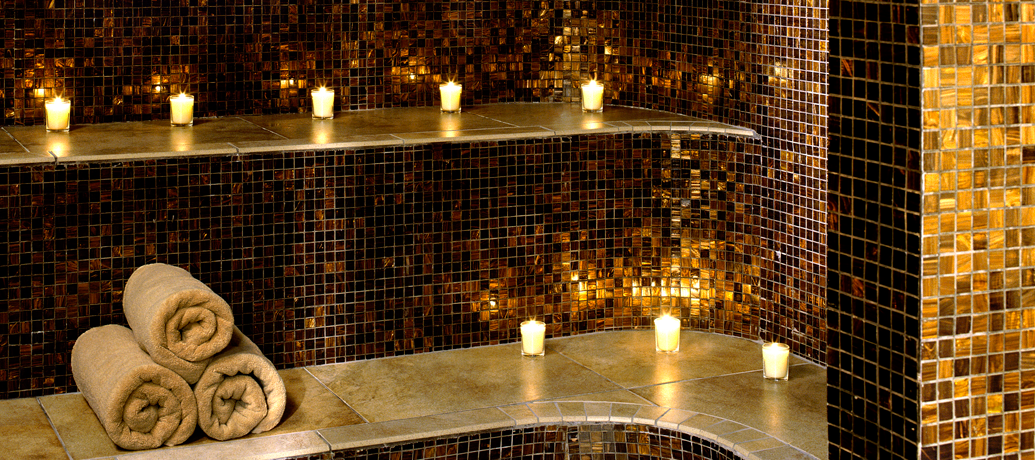 Warm light from lit candles sets the mood in a spa's steam room.