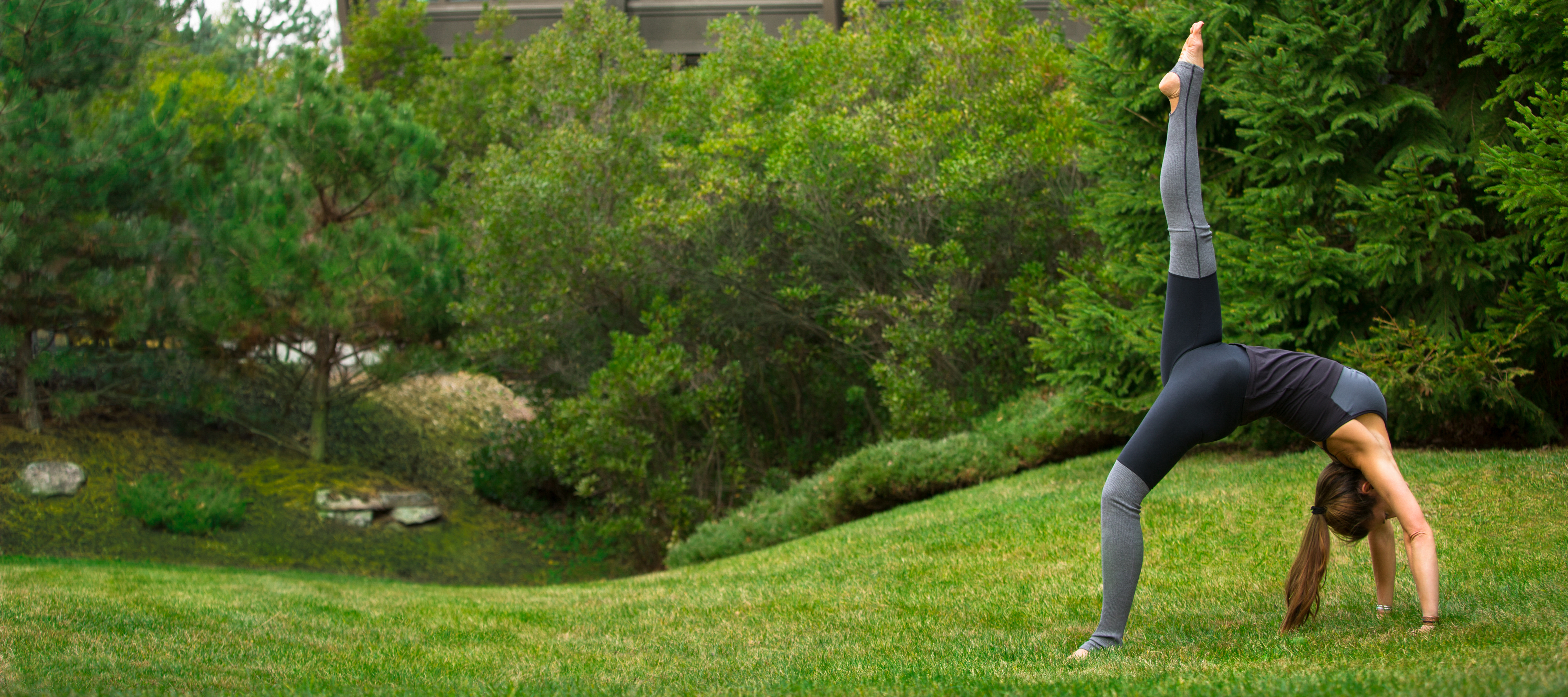 A woman practicing yoga outside in the grass during her vacation retreat.