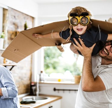A father holding his son up in the air as they play together.