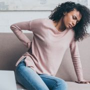 A tense woman holding her back in pain due to her poor posture.