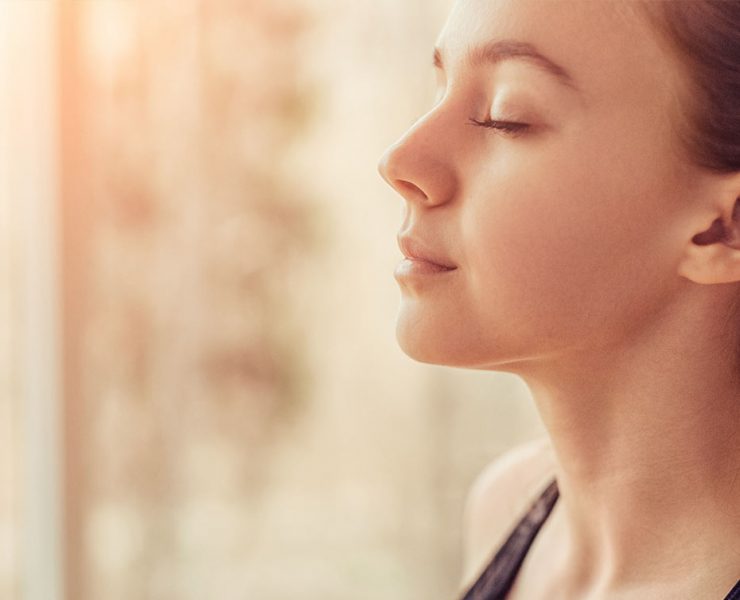 A woman sitting with her eyes closed meditating.
