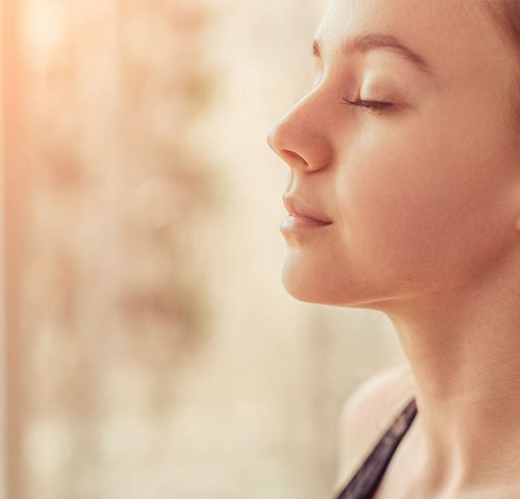 A woman sitting with her eyes closed meditating.