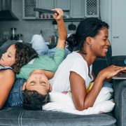 A mother sitting down at her computer while her children play behind her.