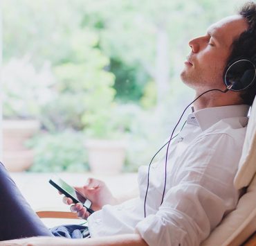 A man sitting at his desk listening to music to relax and ease his pain.