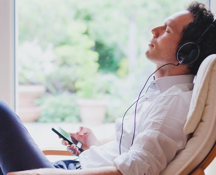A man sitting at his desk listening to music to relax and ease his pain.