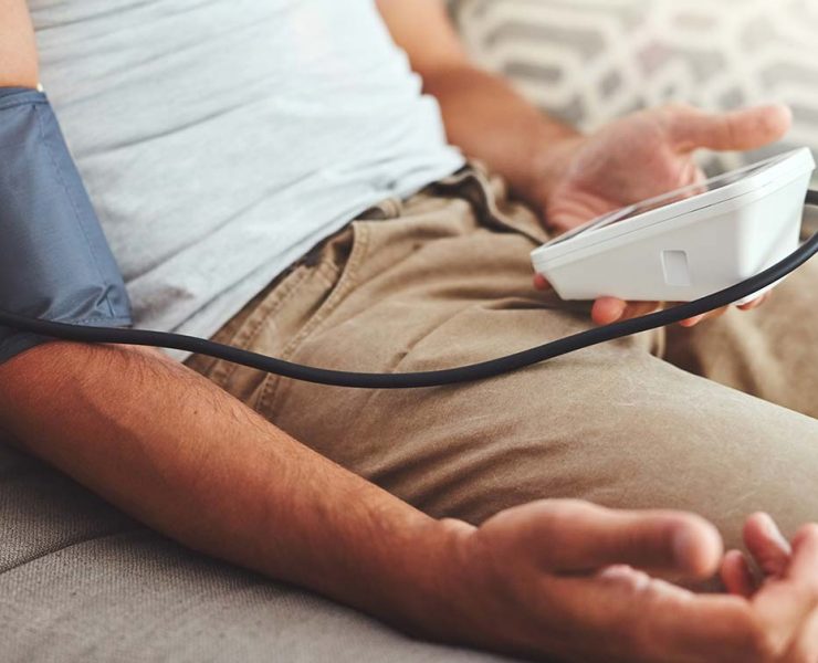 A man checking his blood pressure to see if he's experiencing hypertension.