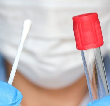 A provider holding a cotton swap and a vial to perform a patient's COVID-19 testing.