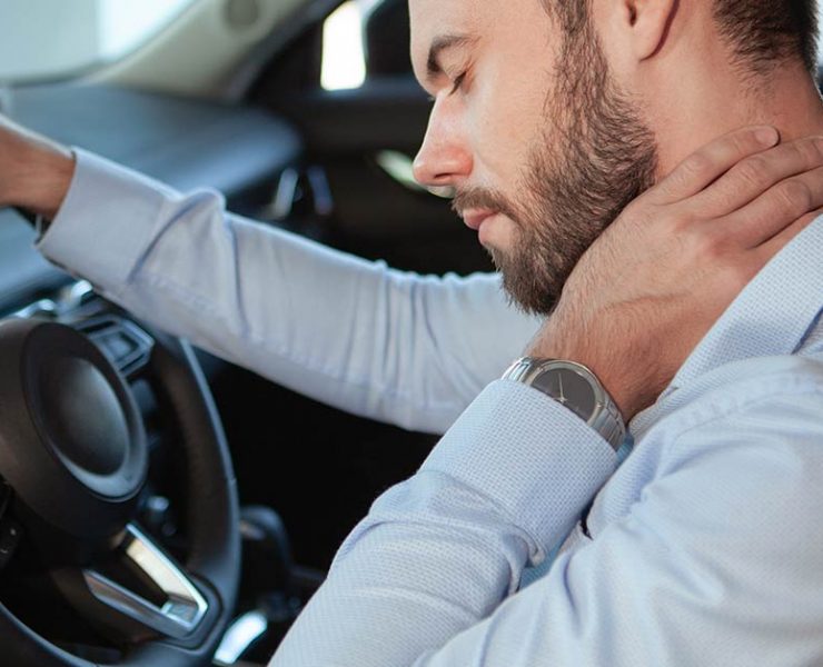 A man holding his neck in pain from lack of stretching while driving.