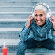 A woman smiling as she sits on some steps outside while taking a break from exercising.