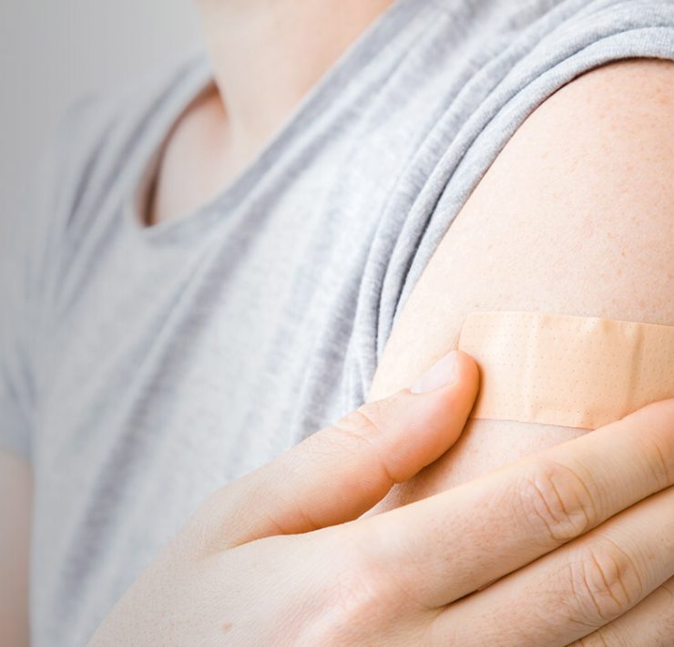 A woman with a bandaid on her arm to stop the bleeding from where she was vaccinated.