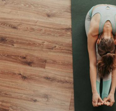 A woman stretching and doing yoga to alleviate her back pain.