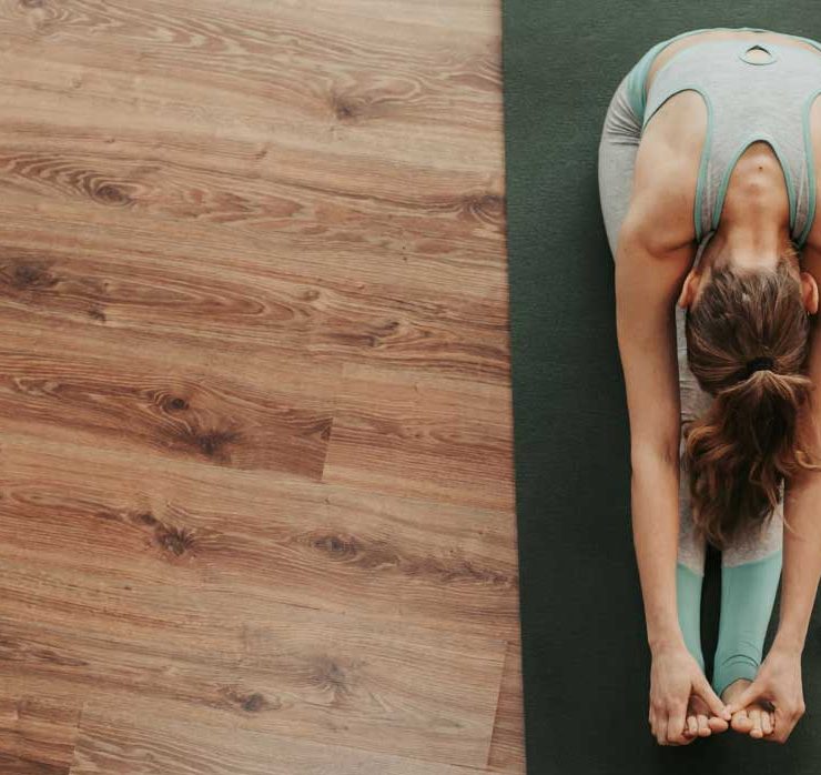 A woman stretching and doing yoga to alleviate her back pain.
