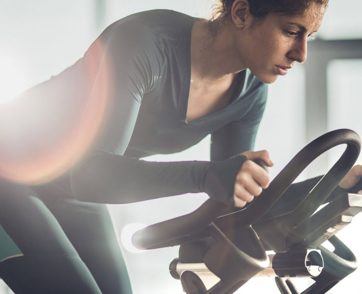 A woman working out on her stationary bicycle after finishing her stretches.