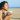 A woman having a drink on the beach as she prasctices mindfulness and takes the time to check in with herself.