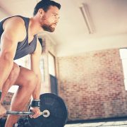 A man looking ahead an lifting weights, making sure to use proper form to avoid back pain and injury.