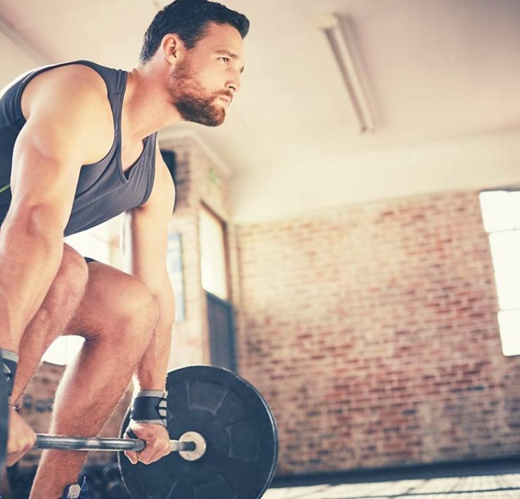 A man looking ahead an lifting weights, making sure to use proper form to avoid back pain and injury.