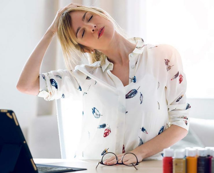 A woman sitting at her desk looking very stressed.