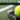 A tennis racket and ball are sitting on the court after the owner sat them down to stretch.