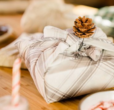 A wrapped holiday gift sitting on the dinner table.