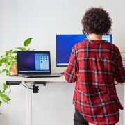 A woman working at her standing desk, while it's providing her with ergonomic balance.