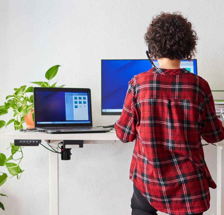 A woman working at her standing desk, while it's providing her with ergonomic balance.