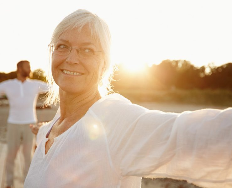 An elderly couple smiling and dancing outside after their massage therapy session for aging individuals.