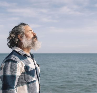 Man looking peaceful in front of the ocean - lowering cortisol naturally